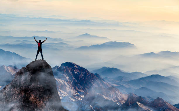 Young man enjoys success on top of a cliff